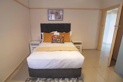 a bedroom with a large bed with orange pillows at Colourfully cosy in Pretoria