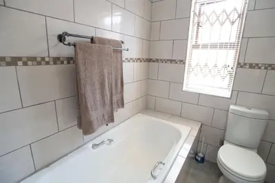 a white bathroom with a tub and a toilet at Colourfully cosy in Pretoria
