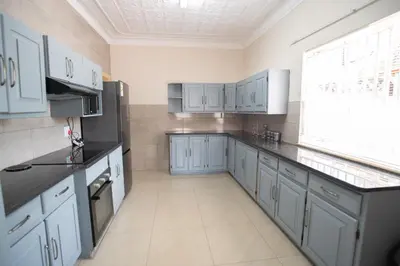 a large kitchen with blue cabinets and a window at Colourfully cosy in Pretoria
