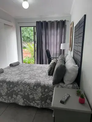 a bedroom with a bed with a table and a window at Kuntuala House in Pretoria