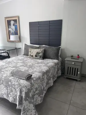 a bedroom with a large bed and a night stand at Kuntuala House in Pretoria