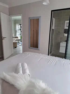 a white bed with two towels and a mirror at THE BLYDE Holiday Apartments in Pretoria