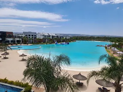 a large swimming pool with umbrellas and a beach at THE BLYDE Holiday Apartments in Pretoria