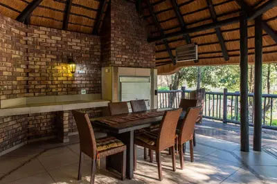 a dining room with a table and chairs on a patio at Kruger Park Lodge Unit No. 209 in Hazyview