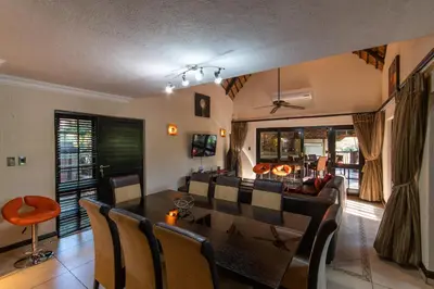 a dining room and living room with a table and chairs at Kruger Park Lodge Unit No. 209 in Hazyview