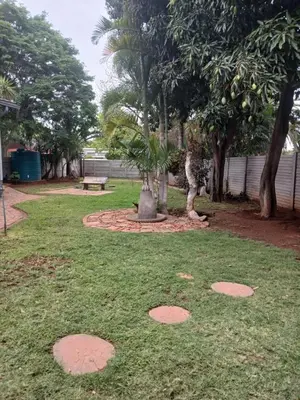 a park with trees and a bench in the grass at Africa Dawn Guesthouse in Musina