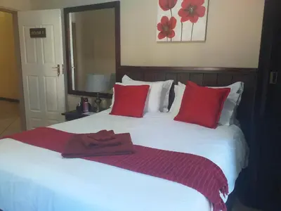 a white bed with red pillows and a towel on it at Africa Dawn Guesthouse in Musina