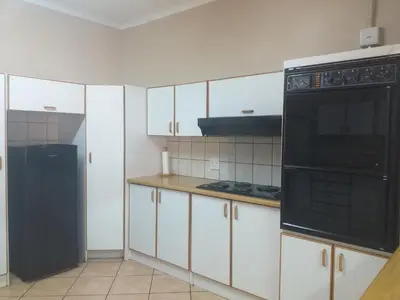 a kitchen with white cabinets and a black appliance at Africa Dawn Guesthouse in Musina