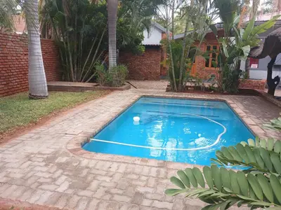 a swimming pool in a yard with a brick wall at Africa Dawn Guesthouse in Musina