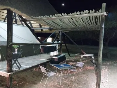a tent with chairs and a stove on a deck at Unathi Game Lodge in Tshwee