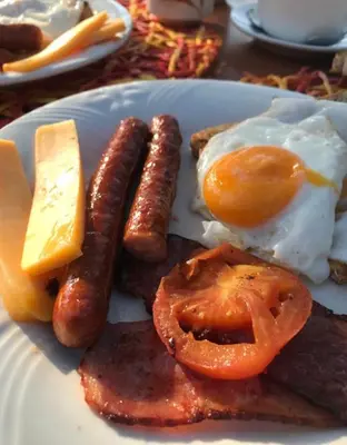 a plate of breakfast food with sausage and eggs at Unathi Game Lodge in Tshwee