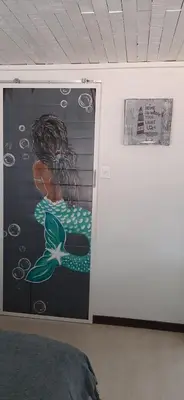 a room with a door with a painting of a mermaid at Cozy Guest in Graskop