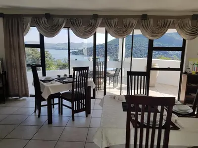 a dining room with a table and chairs and a large window at El Shadai Guest House & Spa Hartbeespoort in Hartbeespoort