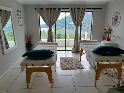 two beds in a room with a large window at El Shadai Guest House & Spa Hartbeespoort in Hartbeespoort
