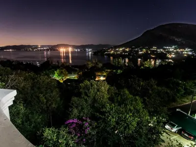 a view of the water and a city at night at El Shadai Guest House & Spa Hartbeespoort in Hartbeespoort