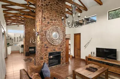 a living room with a stone fireplace and a television at Elements Private Golf Reserve House 197 in Bela-Bela