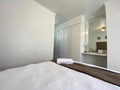a white bedroom with a large bed and a sink at Siena Sun Apartment 4 in Midrand