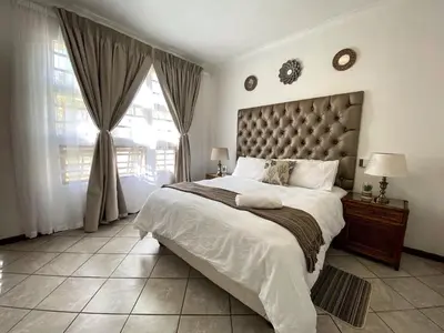 a bedroom with a large bed and a large window at Siena Sun Apartment 4 in Midrand