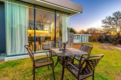 a table and chairs on a lawn with a house at KRAVIT Premier Suites in Midrand
