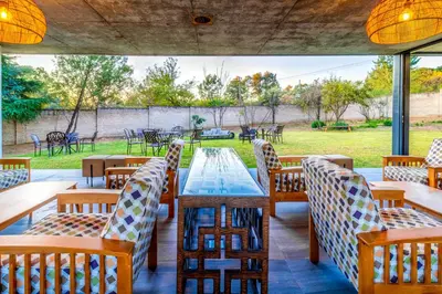 a patio with tables and chairs with a view of a park at KRAVIT Premier Suites in Midrand