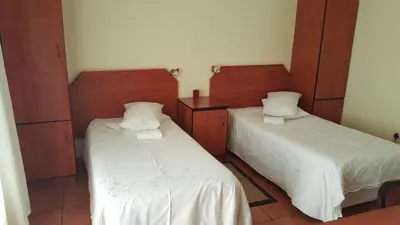 two beds in a room with white sheets at Deletz Guesthouse in Witbank
