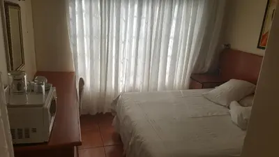 a bedroom with a bed and a window with white curtains at Deletz Guesthouse in Witbank
