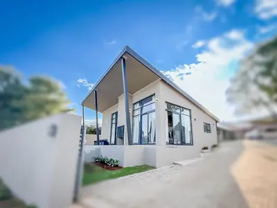 a small white house with windows on a street at Dorpshuis in Dullstroom