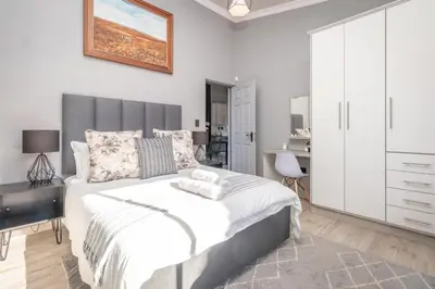 a bedroom with a large bed with a black desk at Dorpshuis in Dullstroom