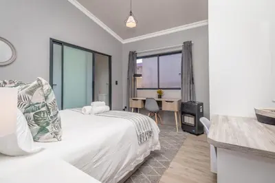 a hotel room with a bed and a desk and a table at Dorpshuis in Dullstroom