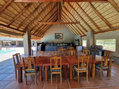 a dining room with a large wooden table and chairs at Thandolwami Bushlodge in Hoedspruit