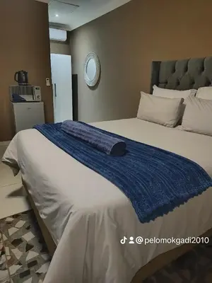 a bed with a blue blanket on top of it at Soma Guesthouse in Groblersdal