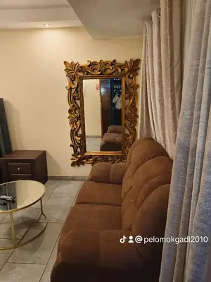a living room with a couch and a mirror at Soma Guesthouse in Groblersdal