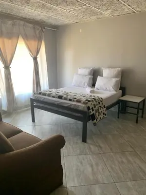 a bed in a room with a couch and a window at Victoria guest house Nyumbani in Tzaneen