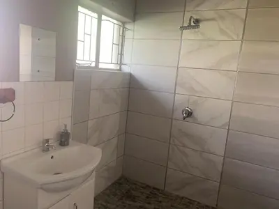 a white bathroom with a sink and a shower at Victoria guest house Nyumbani in Tzaneen