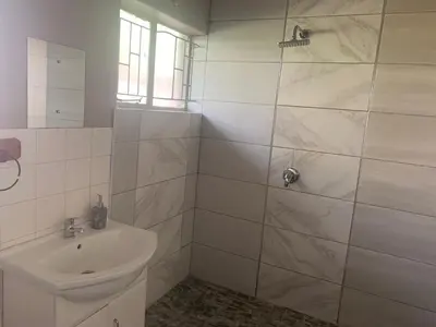 a white bathroom with a sink and a shower at Victoria guest house Nyumbani in Tzaneen