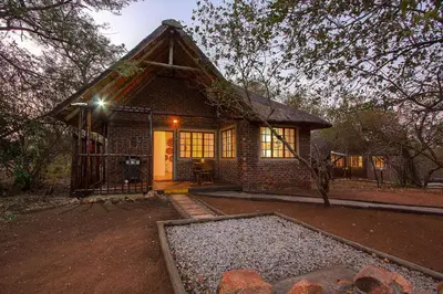 a small house with a thatched roof at South Safari Lodge in Marloth Park