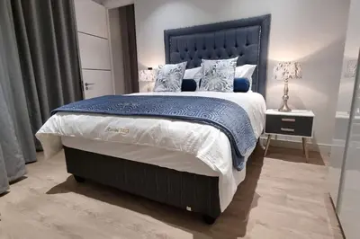 a bedroom with a large bed with blue and white pillows at Ellipse Waterfall - The Loft at Cassini in Midrand