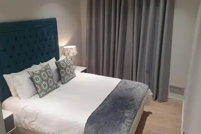 a bedroom with a large bed with a blue headboard at Ellipse Waterfall - The Loft at Cassini in Midrand