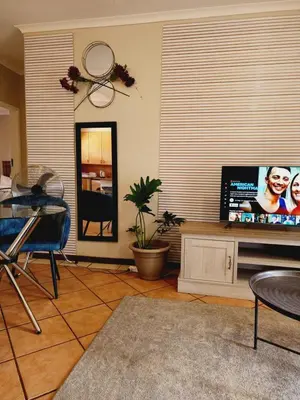 a living room with a tv and a mirror at Shepherd Tree in Pretoria
