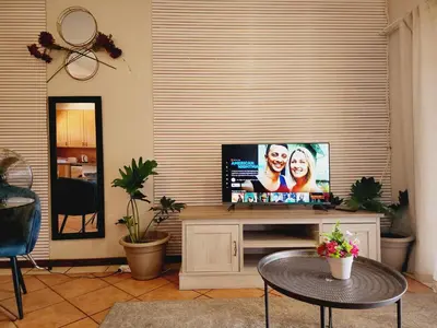 a living room with a flat screen tv on a entertainment center at Shepherd Tree in Pretoria
