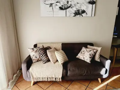 a brown couch sitting in a living room with pillows at Shepherd Tree in Pretoria