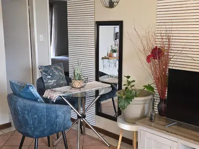 a living room with a table and chairs and a mirror at Shepherd Tree in Pretoria