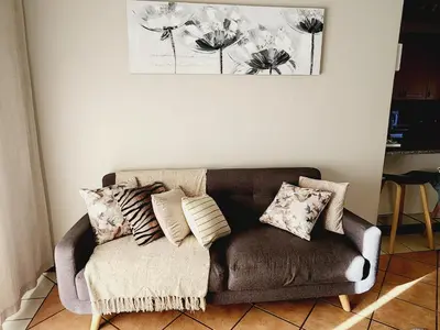 a couch in a living room with pillows on it at Shepherd Tree in Pretoria