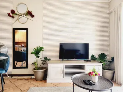 a living room with a flat screen tv on a entertainment center at Shepherd Tree in Pretoria
