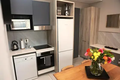 a kitchen with a table with a vase of flowers on it at Menlyn Trilogy - 2 Bedroom & Great Views - No Loadshedding in Pretoria