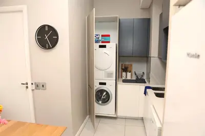 a kitchen with a washing machine and a clock at Menlyn Trilogy - 2 Bedroom & Great Views - No Loadshedding in Pretoria