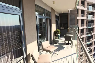 a balcony with chairs and tables on a building at Menlyn Trilogy - 2 Bedroom & Great Views - No Loadshedding in Pretoria