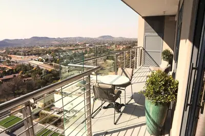 a balcony with a table and a view of a city at Menlyn Trilogy - 2 Bedroom & Great Views - No Loadshedding in Pretoria