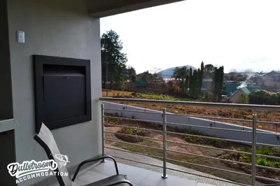 a balcony with a flat screen tv and a chair at Uitzicht in Dullstroom