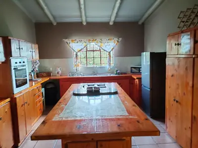 a large kitchen with a wooden table and a window at 83 on De Lange in Graskop